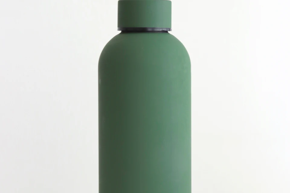 Grüne Trinkflasche aus Edelstahl vor hellem Hintergrund